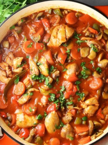 Top down view of chicken goulash in large shallow white pan.
